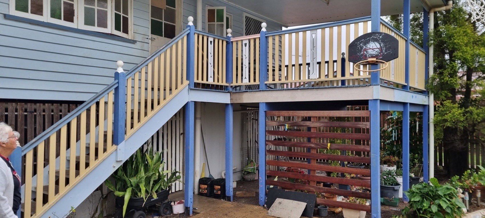 A raised timber home with a rebuilt deck, stairs and painted balustrade