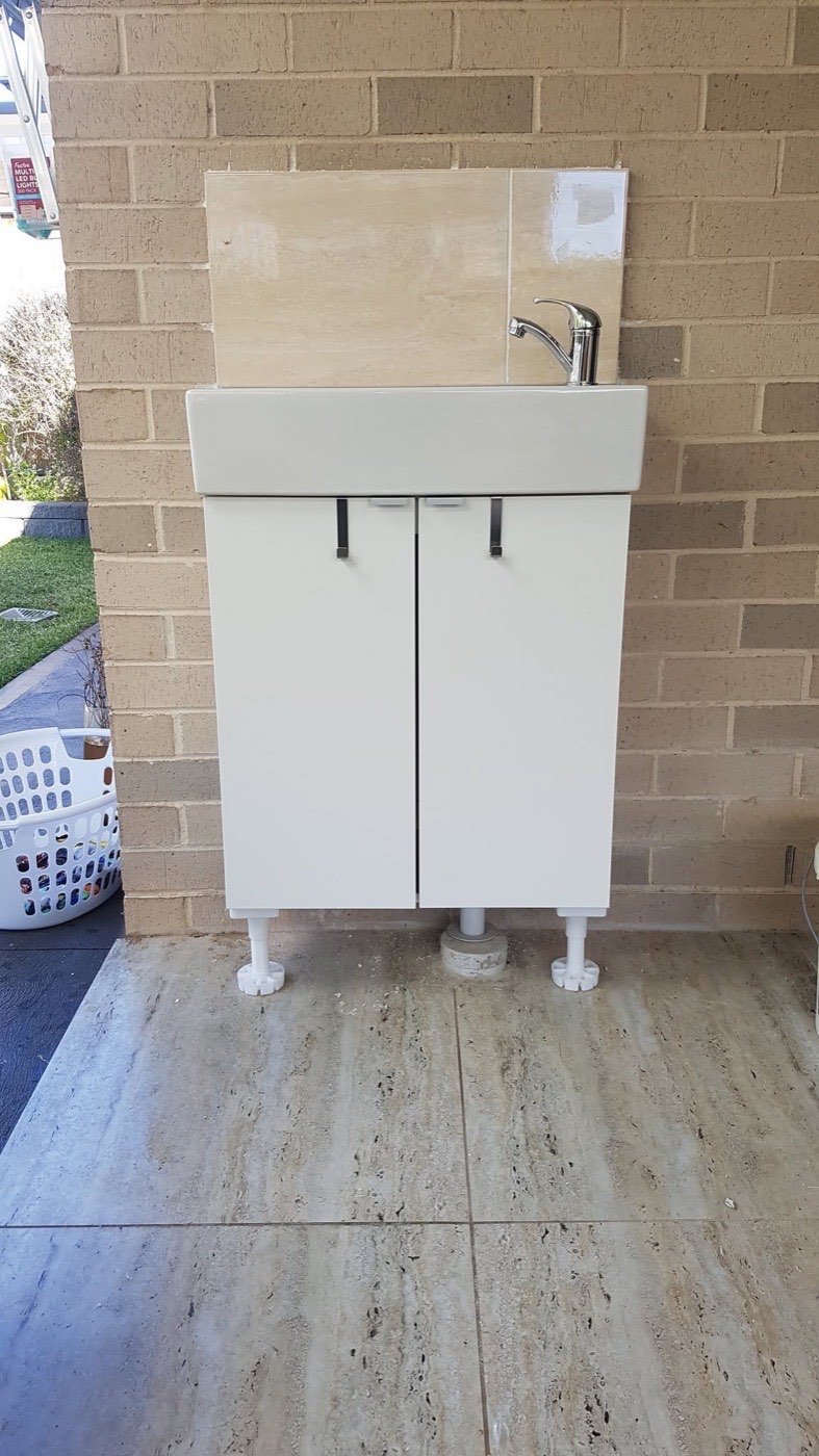 A new laundry vanity cabinet fitted against a rendered block wall