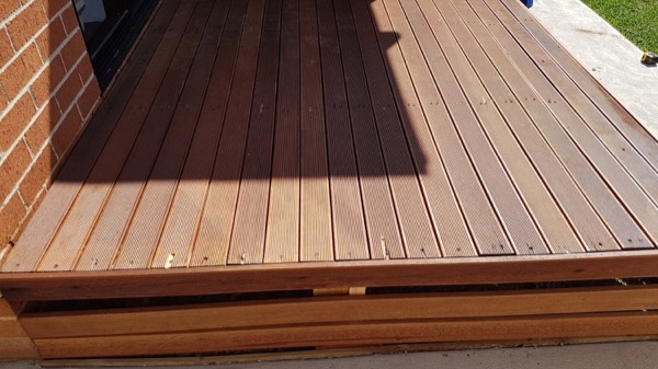 A hardwood deck stained a deep red-brown in full sun