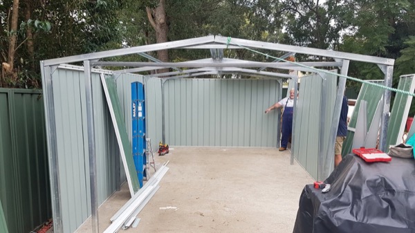 A garden shed part way through assembly on a slab