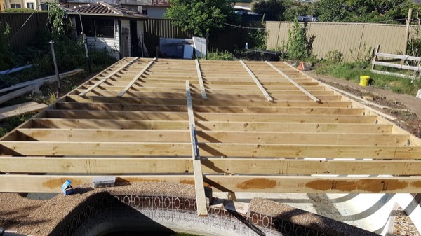 Deck joists laid out across a backyard