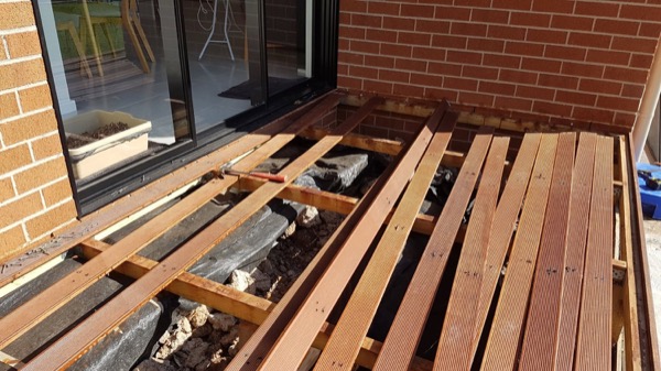 Decking boards being laid over joists at a brick house