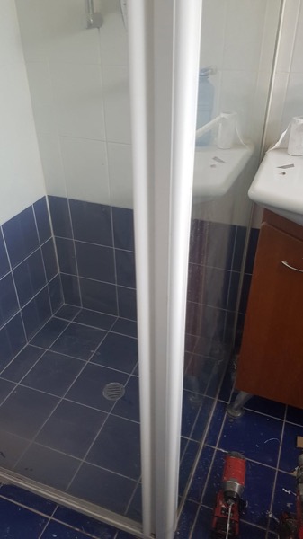 A bathroom with tiled walls and a glass shower screen