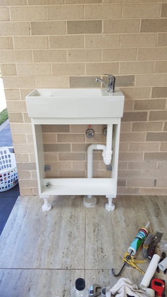 A laundry tub and cabinet with the plumbing connected