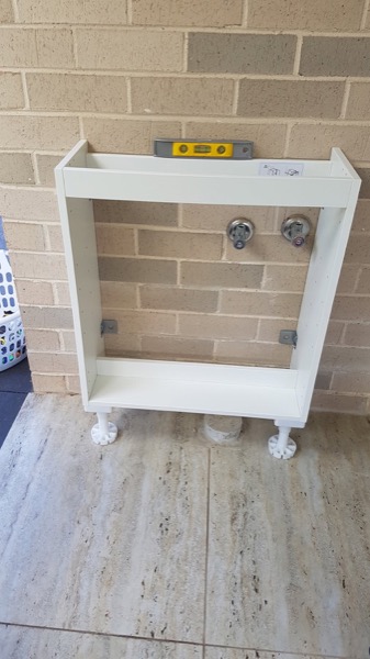 A white laundry cabinet standing ready to be fitted