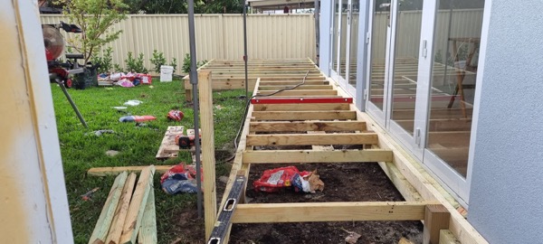 Deck joists running out from a house wall across a lawn