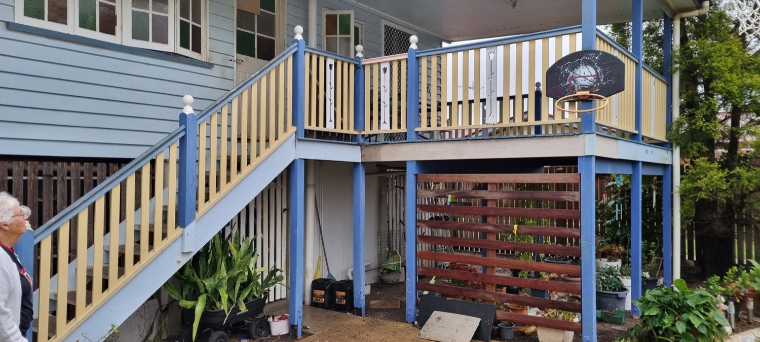 A raised Queenslander with a rebuilt timber deck, stairs and balustrade