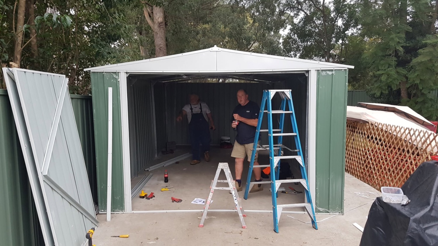 An assembled garden shed on a concrete slab with the doors open